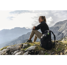 Femme assise avec un sac à dos à la montagne et admire la vue