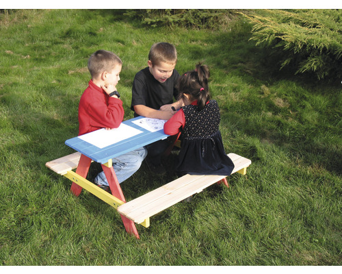 Kinder sitzen an einem farbenfrohen Picknicktisch aus Holz im Garten.