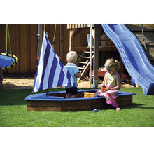 Des enfants jouent dans un bac à sable avec une voile sur une aire de jeux avec une tour de jeux et un toboggan