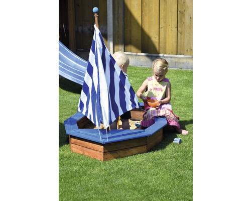 Bac à sable en forme de bateau avec deux enfants dans le jardin.