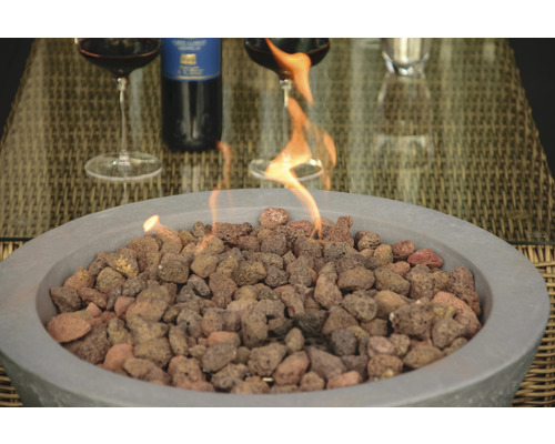 Feuerstelle mit Lavasteinen, zwei Weingläser und eine Weinflasche auf einem Tisch