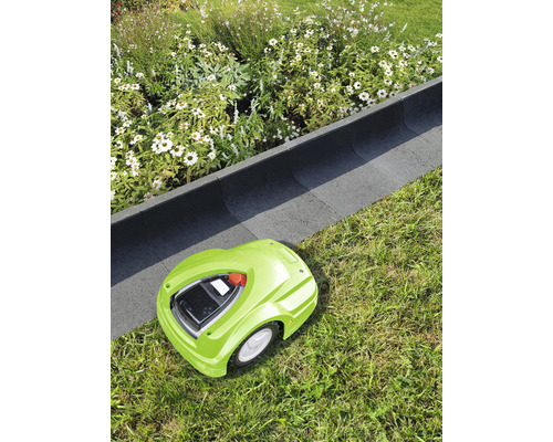 Robot tondeuse à gazon vert sur pelouse à côté d''une bordure de parterre.