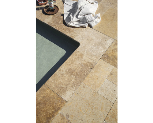 Detailaufnahme von Travertinplatten neben einem Pool mit einem Tuch und Getränken