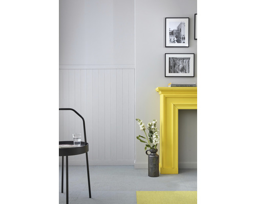 Pièce lumineuse avec des panneaux muraux, un manteau de cheminée jaune, des décorations et une chaise noire.