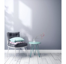 Scène avec une chaise avec des coussins et une table d''appoint avec un vase de fleurs contre un mur