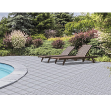 Terrasse mit Steinplatten und zwei Liegestühlen im Garten.