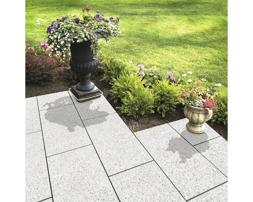 Gartenweg mit Pflastersteinen und bepflanzten Blumentöpfen
