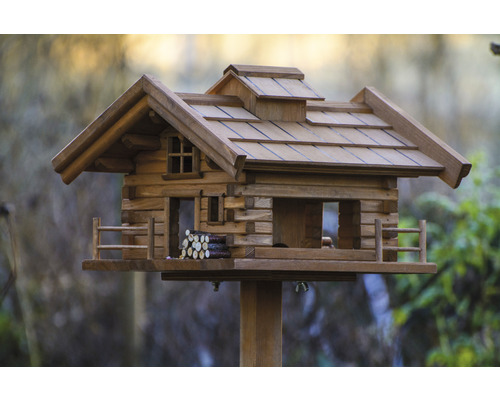 Vogelhaus aus Holz im Blockhausstil mit kleinem Holzzaun
