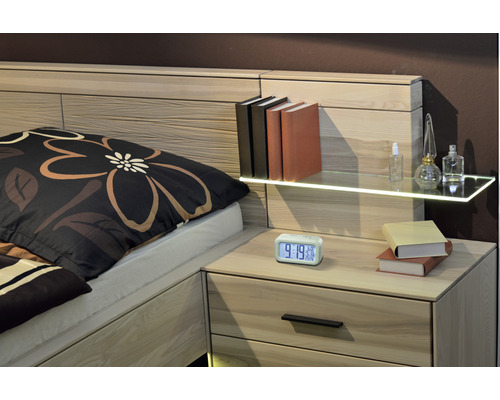 Bett mit Nachttisch, Büchern, Wecker und Dekorationsartikeln