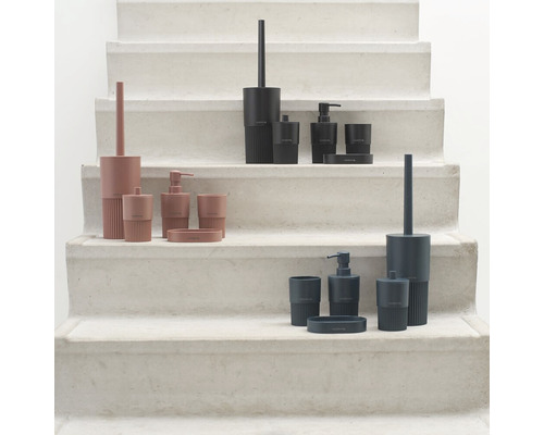 Drei Badezimmer-Sets mit Seifenspender, Becher, Seifenschale und Toilettenbürste auf einer Treppe
