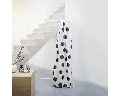 Vorhang mit Punktmuster auf einer Kleiderstange in einem minimalistischen Raum.