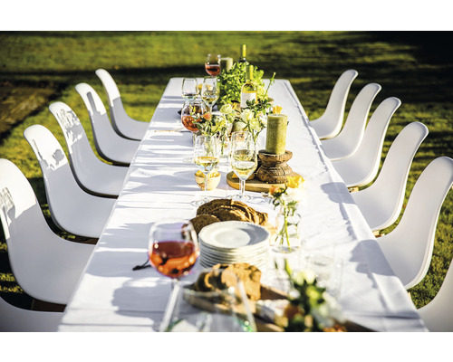 Table à manger dressée avec des chaises blanches à l''extérieur
