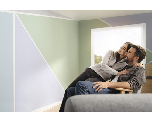 Ein Paar sitzt in einem Zimmer mit geometrischen Mustern an den Wänden.