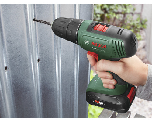 Une personne perce un trou dans une tôle avec une perceuse sans fil. Logo Bosch.