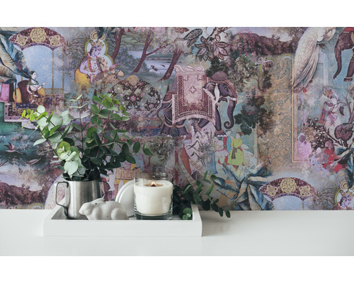 Scène décorative avec papier peint à motifs, bougie, figurine de lapin et eucalyptus dans un pichet