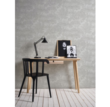 Einrichten mit Schreibtisch, Stuhl, Lampe, Bilderrahmen und Tapete mit Waldmotiv.