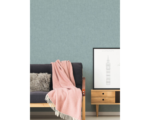 Salon avec papier peint à motifs, canapé, coussin, couverture et petite armoire avec une image de Londres