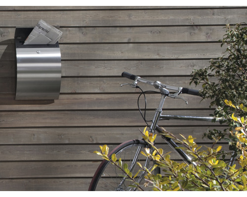 Boîte à journaux en acier inoxydable avec journal sur un mur en bois, à côté d''un vélo