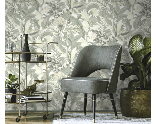 Szene mit floral gemusterter Tapete, Sessel und Barwagen.