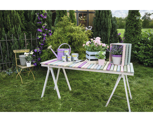 Décoration avec peinture, arrosoir et fleurs sur une table dans le jardin