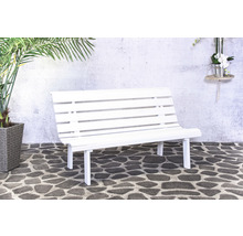 Banc de jardin blanc devant un mur de pierre