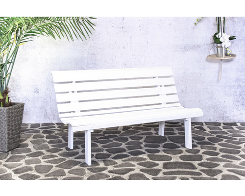 Banc de jardin blanc devant un mur de pierre