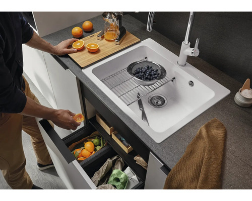 Scène de cuisine avec évier, robinet, poubelle et accessoires pour la préparation de jus d''orange