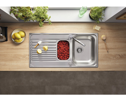 Évier en acier inoxydable avec égouttoir, petit bassin avec des framboises et robinet sur un plan de travail de cuisine