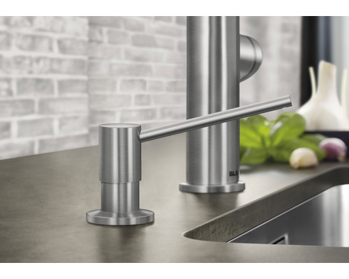 Distributeur de savon en acier inoxydable à côté du robinet de cuisine