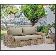 Aménagement paysager de jardin avec un canapé en rotin et des coussins rembourrés