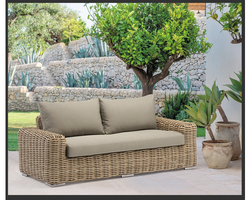 Aménagement paysager de jardin avec un canapé en rotin et des coussins rembourrés