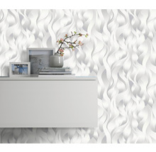 Wohnraum mit weißer 3D-Tapete im Wellendesign, Regal, Bilderrahmen und Dekoration
