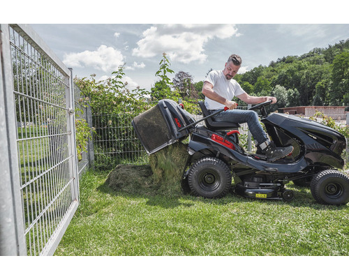Homme vide le bac de ramassage d''un tracteur de pelouse sur une pelouse