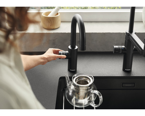 Frau bedient eine schwarze Blanco Küchenarmatur über einer Spüle mit Teekanne