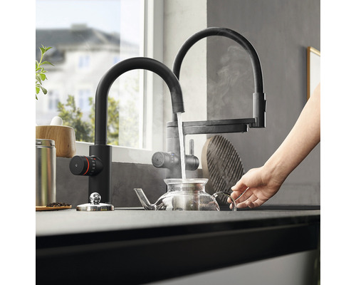 Küchenszene mit schwarzem Wasserhahn, der Wasser in eine Teekanne gießt