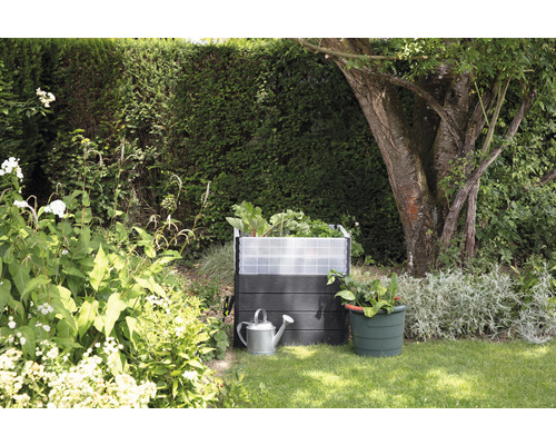 Jardinière surélevée avec arrosoir et pot de fleurs dans le jardin.