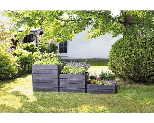 Drei unterschiedlich hohe Pflanzkästen aus Holz im Garten, bepflanzt mit Blumen