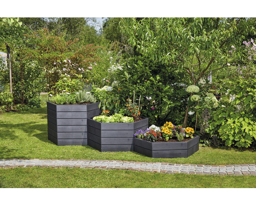 Trois bacs surélevés en bois plantés et étagés dans le jardin.