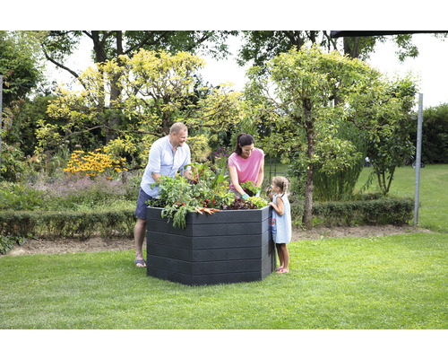 Famille plantant un potager surélevé dans le jardin.