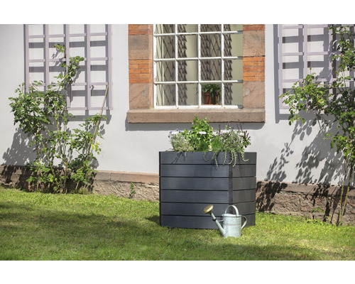 Quadratischer Pflanzkasten aus Holz mit Giesskanne im Garten