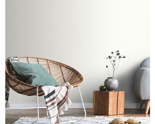 Salon décoratif avec fauteuil en rotin, table en bois et murs clairs