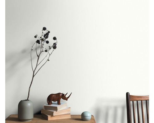 Intérieur avec un arrangement de vase, d''objet de décoration et de pile de livres devant un mur peint.