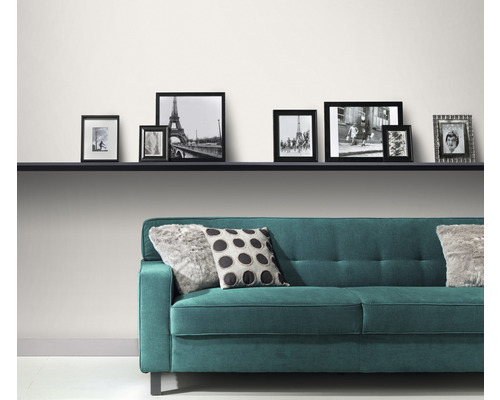 Modernes Wohnzimmer mit türkisfarbenem Sofa, Kissen und einer Reihe von Bilderrahmen auf einem Regal