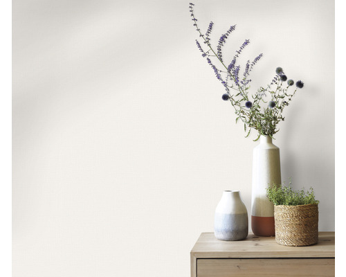 Dekorative Vasen mit Blumen auf einem Holztisch vor einer Wand
