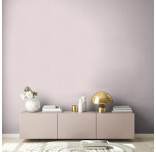 Pièce lumineuse avec mur rose, commode, lampe de table et objets de décoration