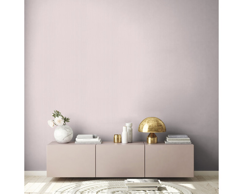 Pièce lumineuse avec mur rose, commode, lampe de table et objets de décoration