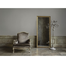 Aménagement intérieur avec fauteuil, miroir et chandelier dans une pièce.