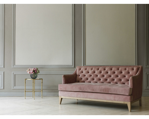 Wohnzimmer mit grau getäfelter Wand, Sofa mit Knopfheftung und Beistelltisch mit Blumen