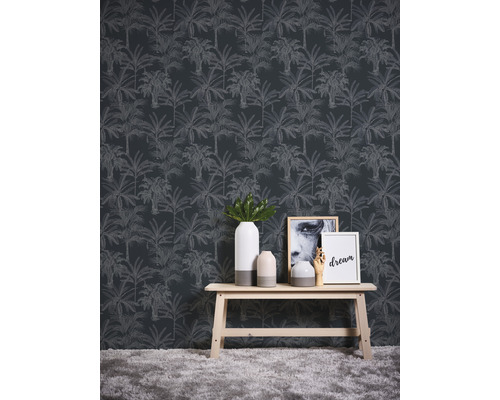 Scène avec un revêtement mural à motifs de palmiers, une table en bois, des vases et des objets décoratifs.