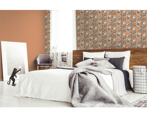 Schlafzimmer mit Bett und gemusterter Tapete mit Affenmotiven